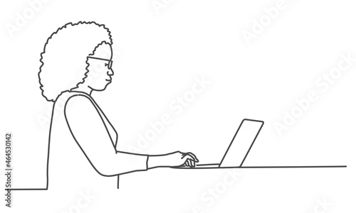 Woman in glasses sitting with laptop computer. Girl writing while sitting in her office.
