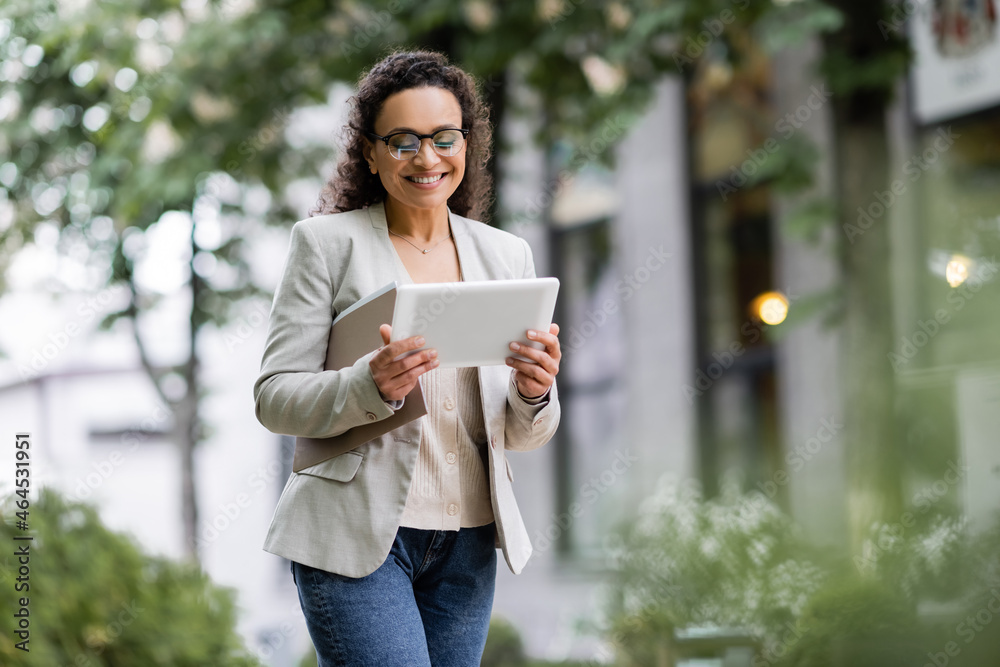 smiling african american businesswoman with documents using digital tablet on urban street smiling african american businesswoman with documents using digital tablet on urban street