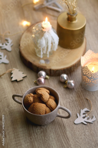 Bowl of cinnamon cookies, lit candles and various Christmas decorations on the table. Selective focus.