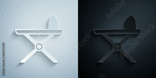 Paper cut Electric iron and ironing board icon isolated on grey and black background. Steam iron. Paper art style. Vector