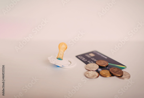 a banking card in hand and some coins, pacifier on white background photo