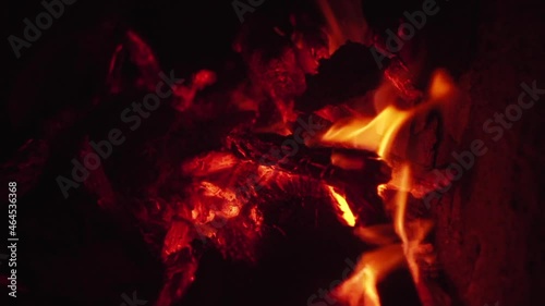 Dry woods smolder in bright camp bonfire in slow motion, with orange flame generating heat on wild beach at dark late night in Vietnam extremely closeup