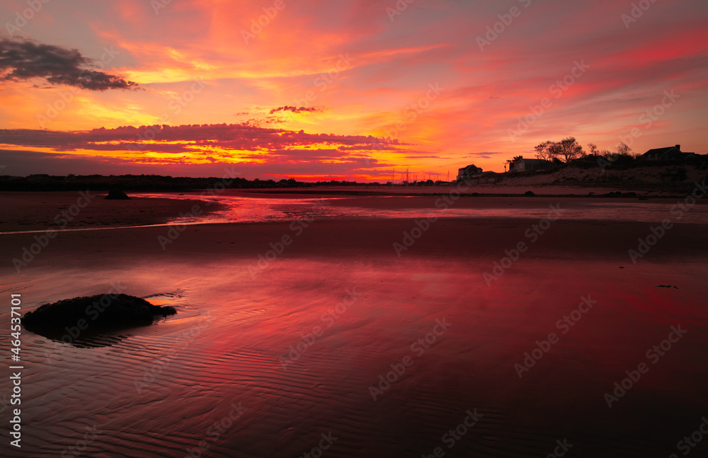 Dramatic seascape at sunrise with pink light reflections on the smooth beach on Cape Cod