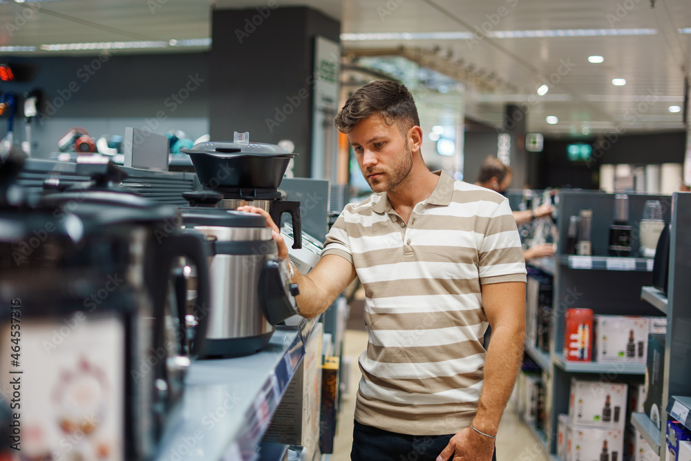 Man choosing multicooker from shelf Man choosing multicooker from shelf