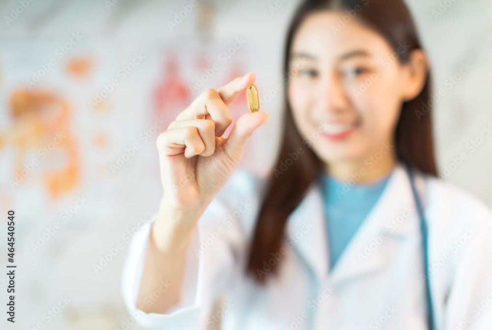 Young asian woman doctor looking at camera.Smiling female pharmacist holding a pill, health care and prevention concept, hand close up. Young asian woman doctor looking at camera.Smiling female pharmacist holding a pill, health care and prevention concept, hand close up.