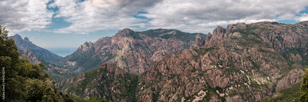 Panoramic view of the rocky mountains of central Corsica with a road in the distance