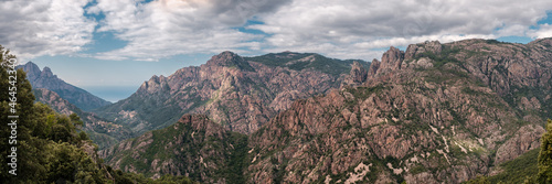 Panoramic view of the rocky mountains of central Corsica with a road in the distance