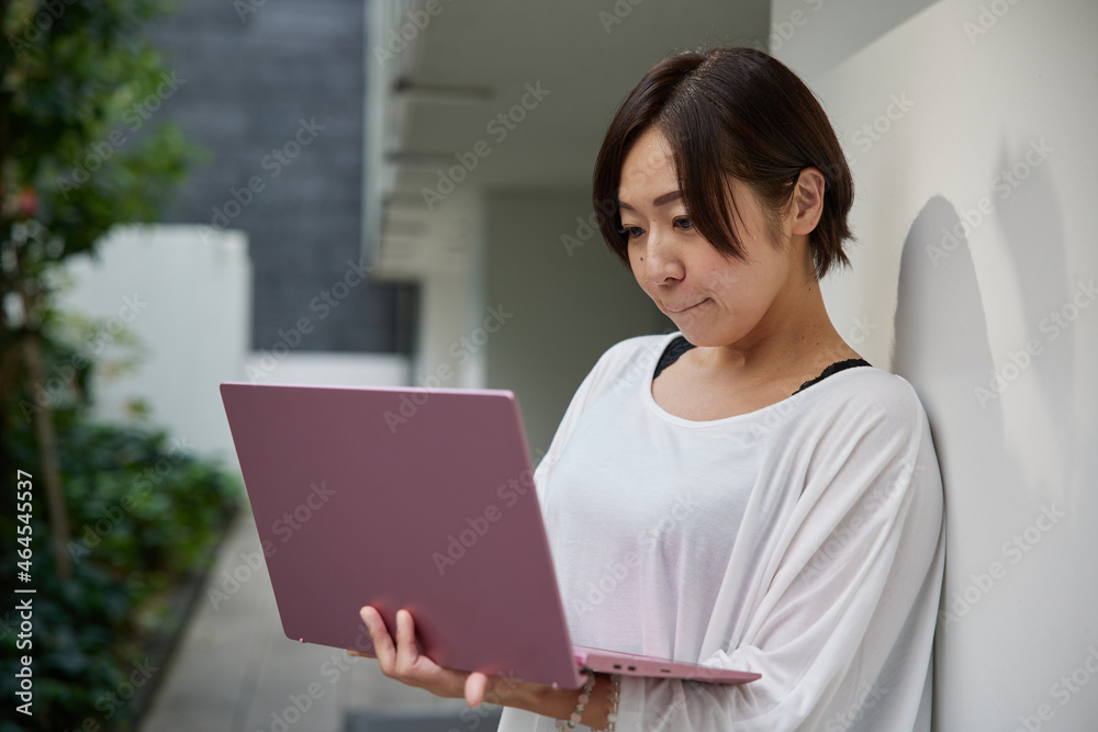 オフィスでノートパソコンを持ちながら仕事をする日本人女性 オフィスでノートパソコンを持ちながら仕事をする日本人女性