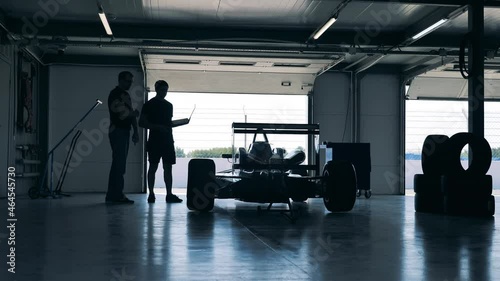 Two professionals are looking at the racing car in the workshop photo