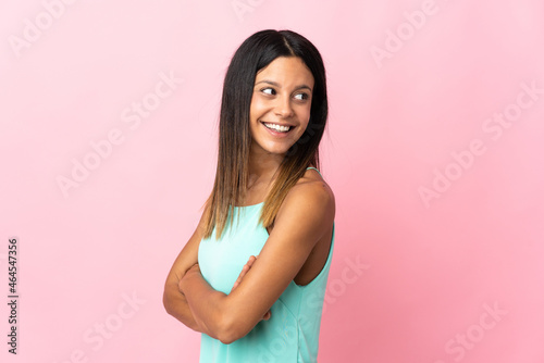 Caucasian girl isolated on pink background with arms crossed and happy
