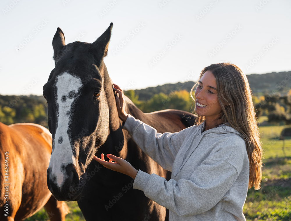 Obraz premium Young woman with her horse in evening sunset light