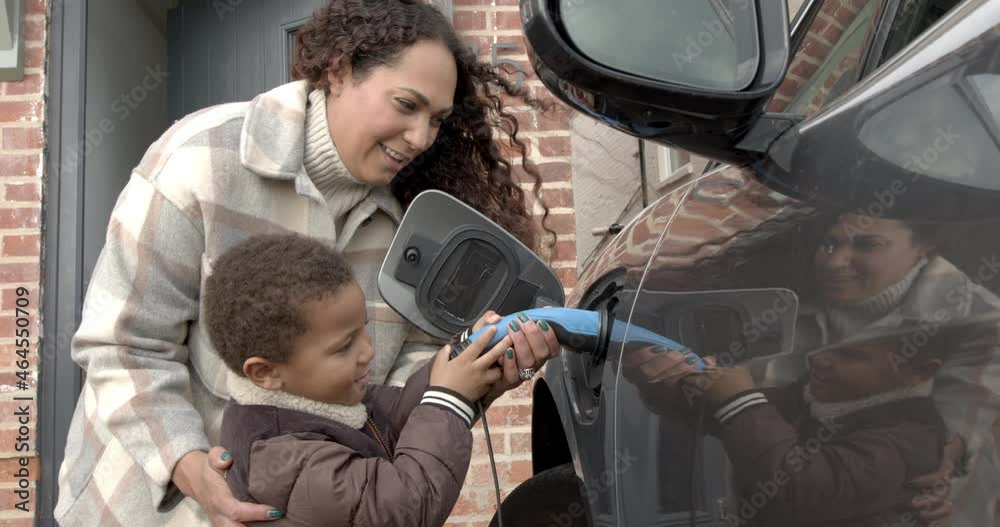 Mother and son charging electric car at home