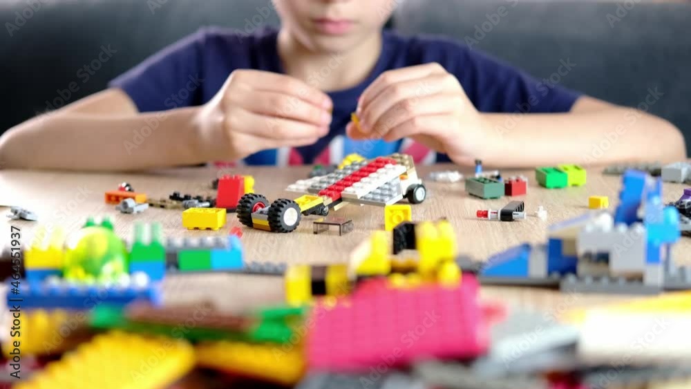 child, kid plays with colored plastic parts of the constructor, creates buildings, equipment, transport, the concept of the development of creativity, fine motor skills, patience and perseverance child, kid plays with colored plastic parts of the constructor, creates buildings, equipment, transport, the concept of the development of creativity, fine motor skills, patience and perseverance