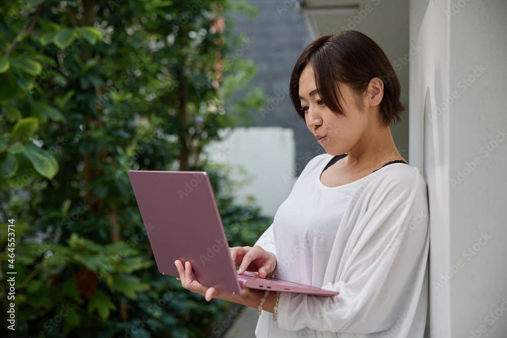 オフィスでノートパソコンを持ちながら仕事をする日本人女性 オフィスでノートパソコンを持ちながら仕事をする日本人女性