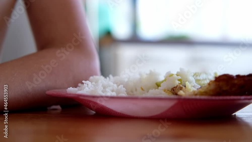close-up of a plate with food on the dining table, a child eats with a fork white rice with tomato sauce and meat steak, selective focus at shallow depth of field photo