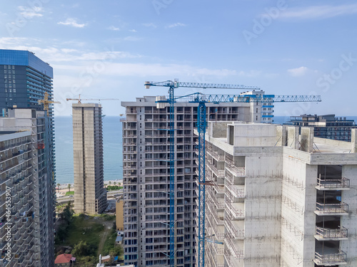 Drone view of the construction of multi-storey buildings on a summer day against the background of the sea.