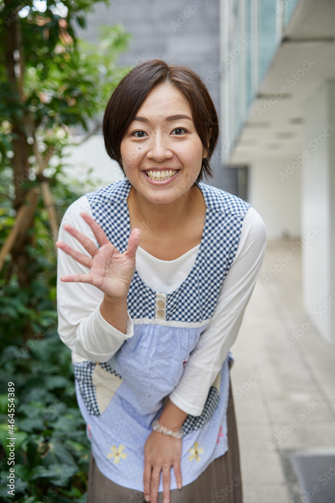 カメラに向かって手を振るエプロンを付けた40代のアジア人女性 Foto De Stock Adobe Stock