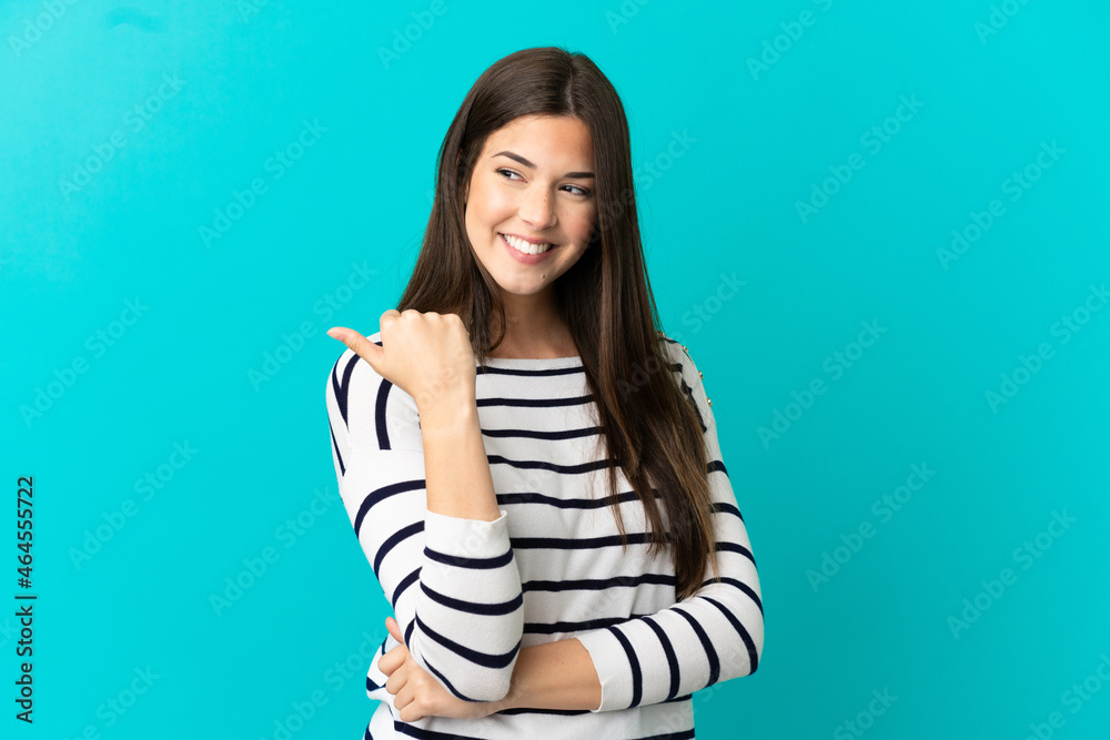 Fototapeta premium Teenager Brazilian girl over isolated blue background pointing to the side to present a product