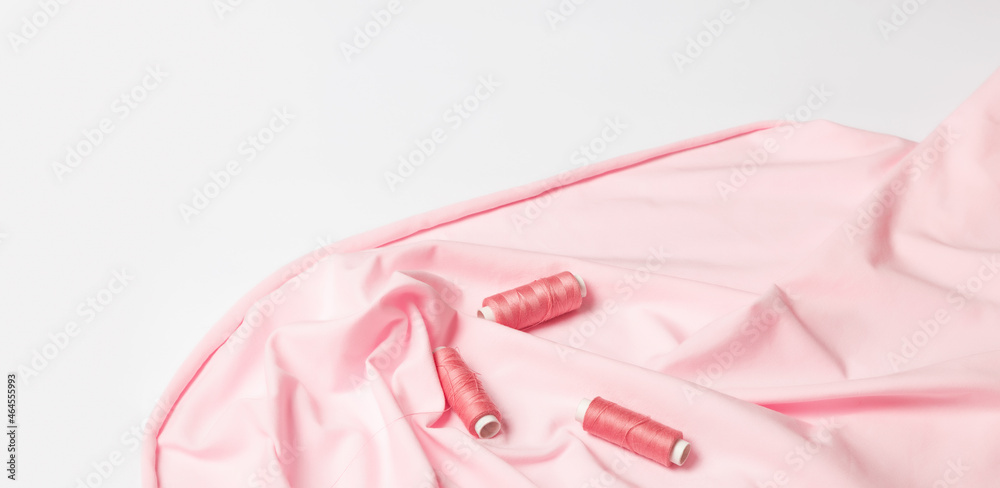 Clothing design. Dressmaking and fashion collection, Tailor's desk. clothes and sewing tools. Pink cloth, threads, spools, on a white background. Banner