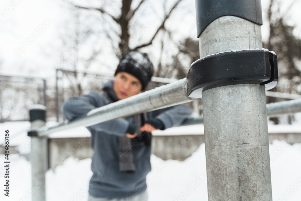 Athletic woman during her winter outdoor workout on parallel bars Athletic woman during her winter outdoor workout on parallel bars