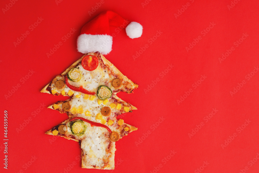 Delicious vegetarian Christmas tree pizza with tomatoes, vegetables and cheese on red background. Creative, funny food concept for kids. Top view, flat lay. Copy space. 