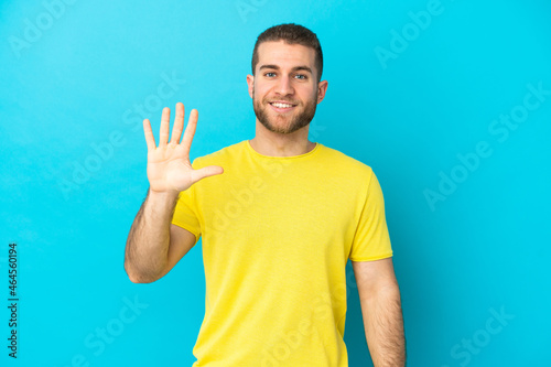 Young handsome caucasian man isolated on blue background counting five with fingers