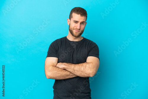 Young handsome caucasian man isolated on blue background feeling upset