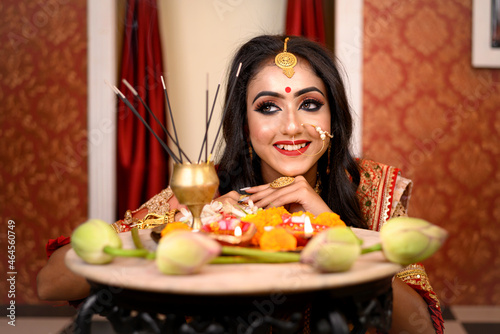 Portrait of pretty young Indian woman wearing traditional saree, gold jewellery and bangles, smiles tender in decorative background. Indian culture, occasion, religion and fashion. photo