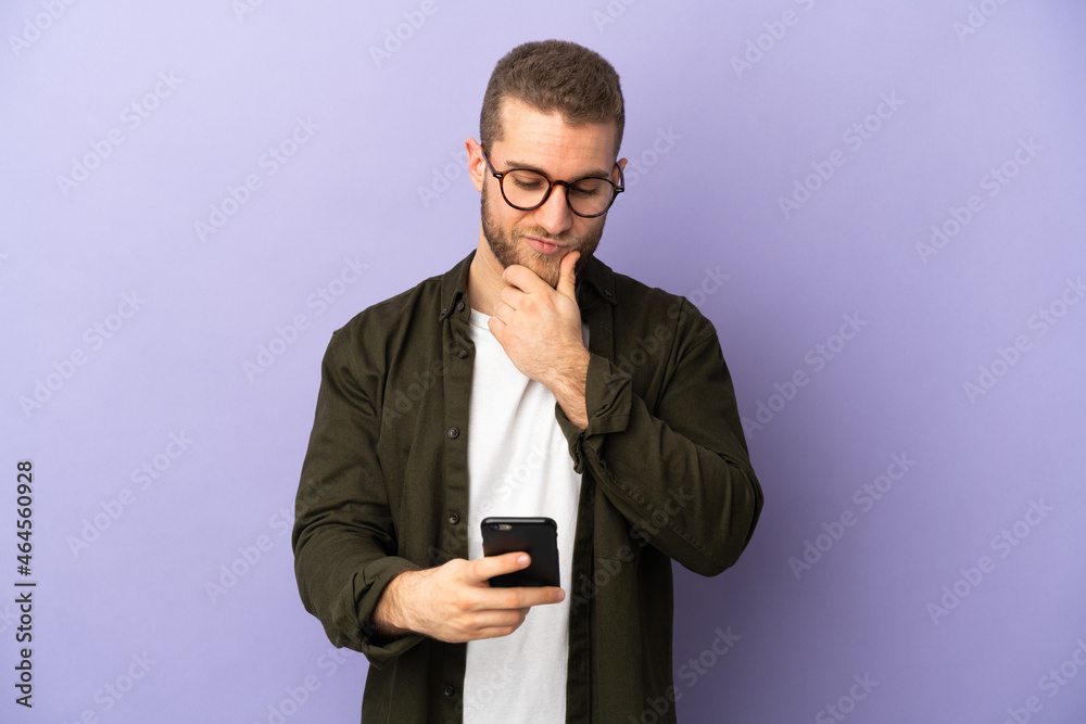 Young handsome caucasian man isolated on purple background thinking and sending a message Young handsome caucasian man isolated on purple background thinking and sending a message