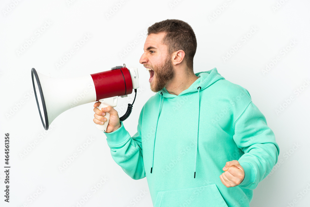 Young handsome caucasian man isolated on white background shouting through a megaphone to announce something in lateral position Young handsome caucasian man isolated on white background shouting through a megaphone to announce something in lateral position
