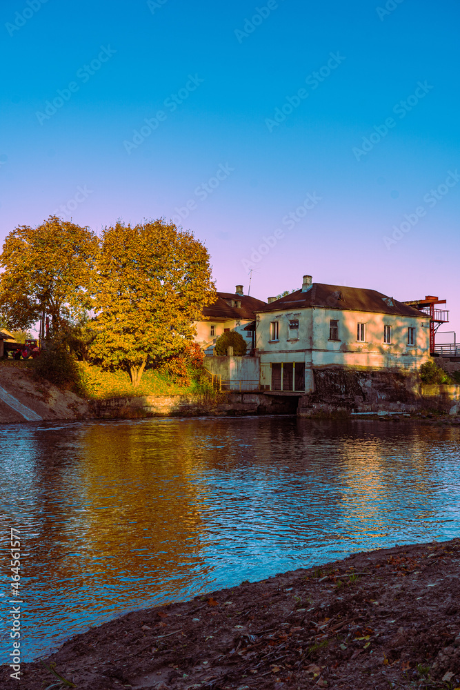 Obraz premium Reflection of the home and golden trees in the river water.