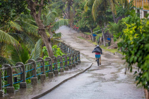 A man rides a bicycle in the pouring rain. Tropical rain, cold cyclone, storm warning.