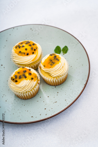 passion fruit cupcakes decorated by a piping bag white cream on a dish and a marble background