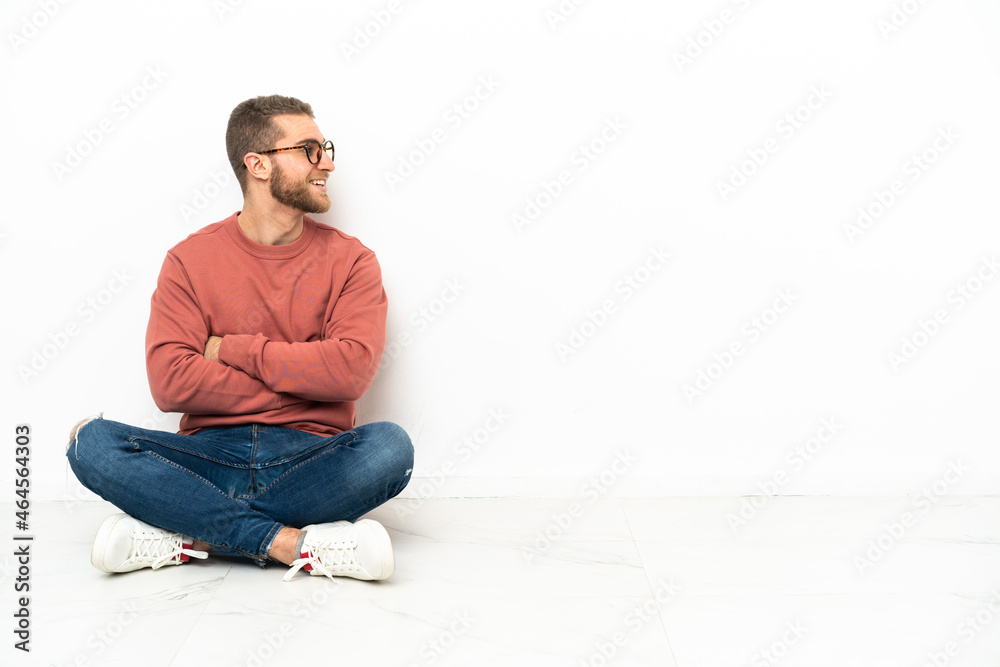 Young handsome man sitting on the floor with arms crossed and happy Young handsome man sitting on the floor with arms crossed and happy