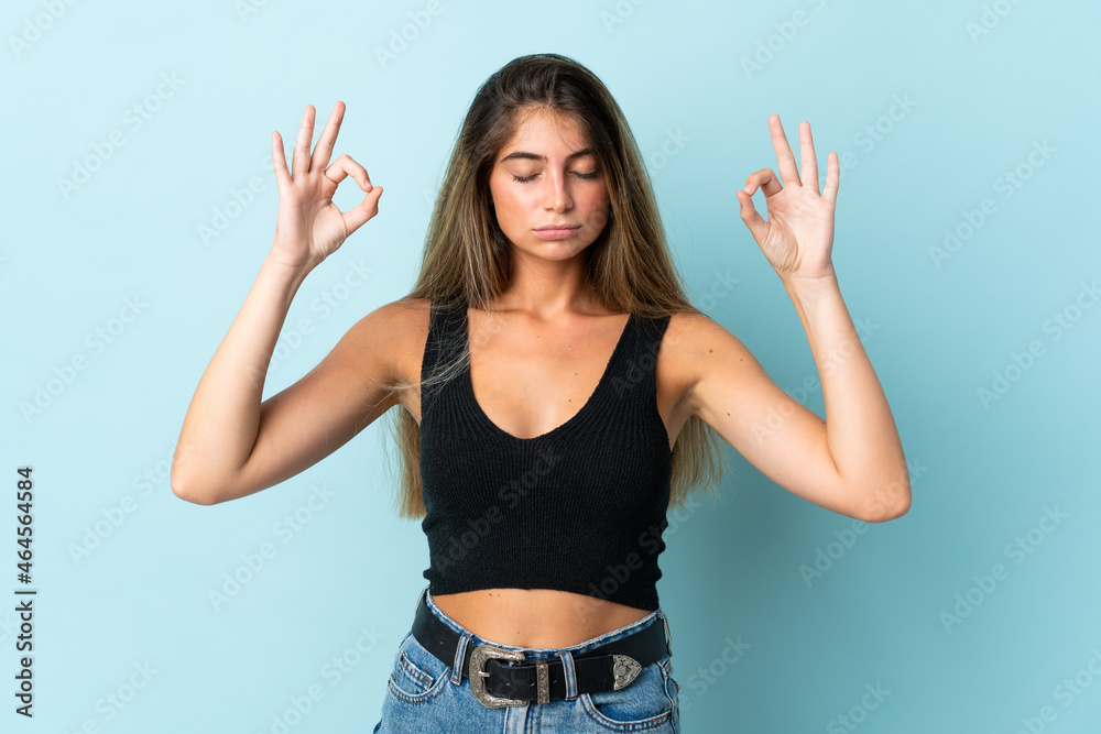 Young caucasian woman isolated on blue background in zen pose Young caucasian woman isolated on blue background in zen pose