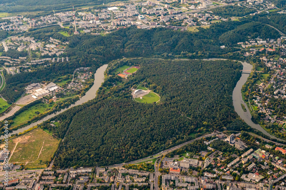 View from hot air balloon on famous Vingis park in Vilnius, Lithuania with huge modern Amphitheater in center of park surrounded by natural pine forest and flowing Neris river.