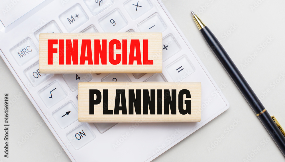 Wooden blocks with the text FINANCIAL PLANNING lie on a light background on a white calculator. Nearby is a black handle. Business concept Wooden blocks with the text FINANCIAL PLANNING lie on a light background on a white calculator. Nearby is a black handle. Business concept