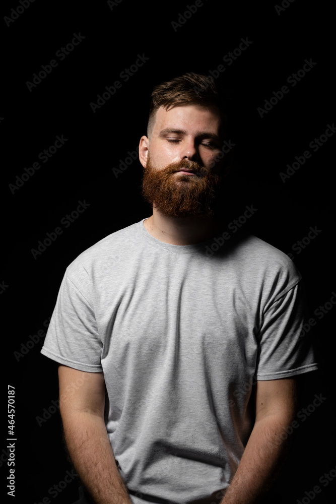 Close-up portrait of a handsome a brunette brutal bearded man in a grey t-shirt. Stylish and handsome man with a beard.