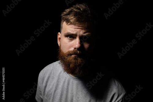 Close-up portrait of a handsome a brunette brutal bearded man in a grey t-shirt. Stylish and handsome man with a beard.