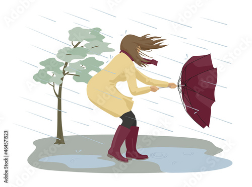 Dangerous condition with rain and wind. A woman tries to hold onto her umbrella during a strong storm. 