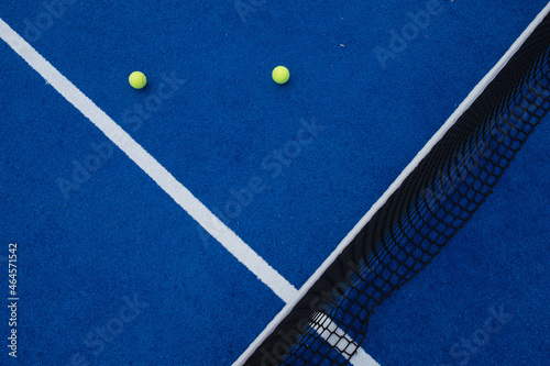 Two balls next to the service line and the net of a paddle tennis court © Vic