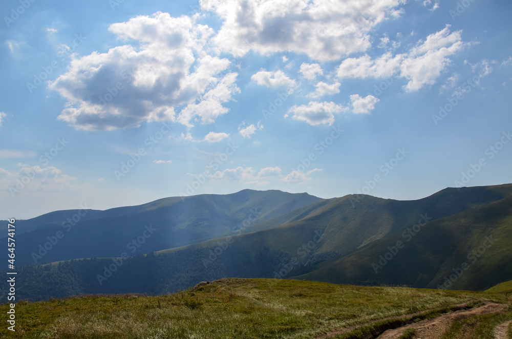 Amazing sunny landscape with grass green hills at Carpathian mountains under blue sky. Borzhava ridge, Ukraine