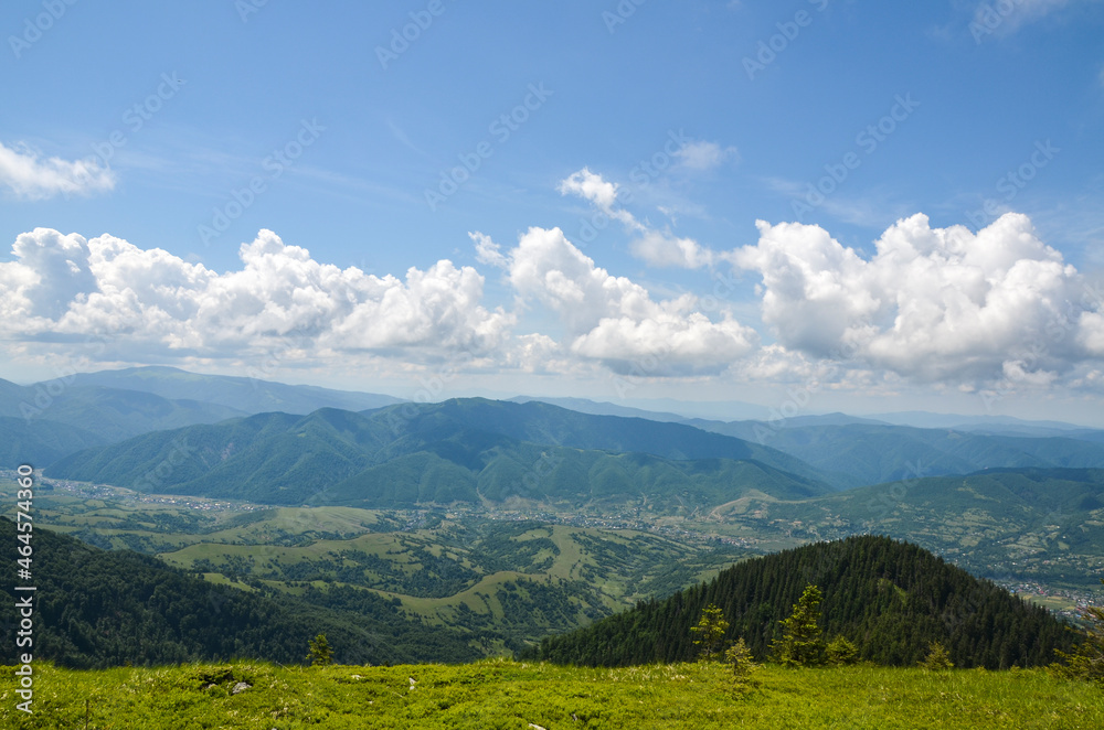 Beautiful view from the mountain ridge to the village in the valley near Carpathian mountains at the summer day. Ukraine