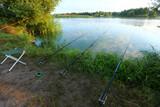 Row of fishing rods at the morning spring lake