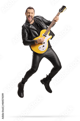 Man in leather clothes playing an electric guitar and jumping