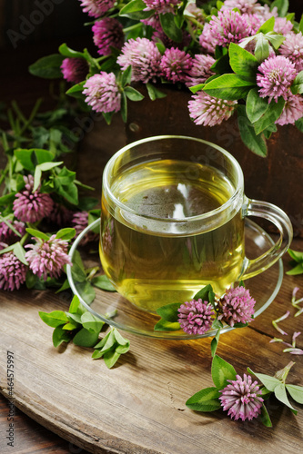 Red clover tea in glass cup on wood on rustic background, herbal drink is good for menopause, bone, heart health and for skin and hair care, closeup, naturopathy and natural medicine concept