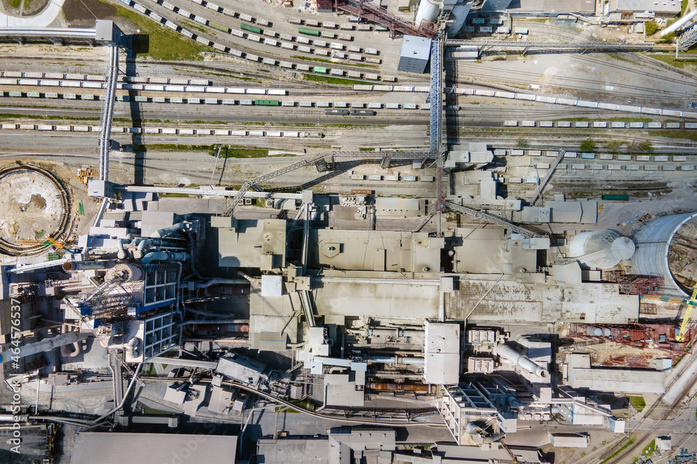 Aerial view of cement plant with high concrete factory structure and tower crane at industrial production area. Manufacture and global industry concept.