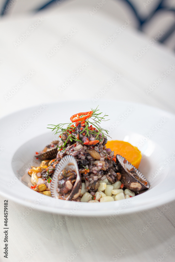 Black ceviche with shell, very typical in Peru. on white plate.
