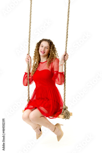 Beautiful girl in red nice dress swinging on swing