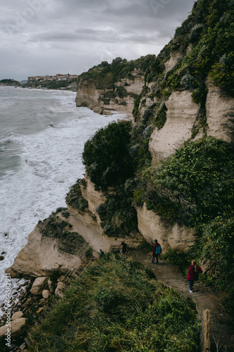 Wanderer laufen bei tosender Brandung die Steilküste von Tropea hinab mit Blick auf die Stadt, Kalabrien, Italien photo